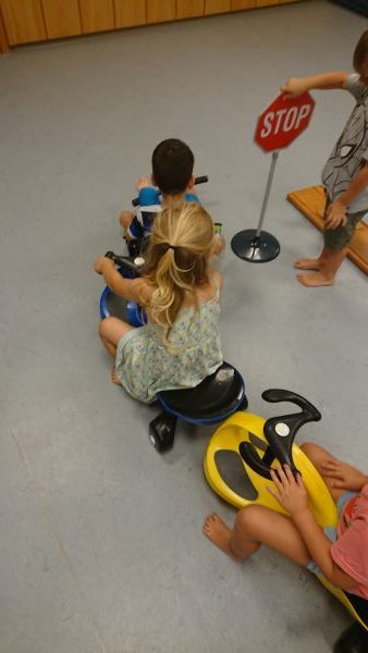 Kinder mit Spiel-Fahrzeugen und Stop-Schild