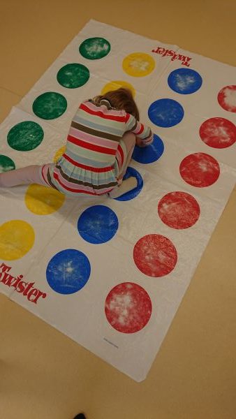 Kind beim Twister spielen: Hände und Füße auf bestimmten farbigen Punkten positionieren