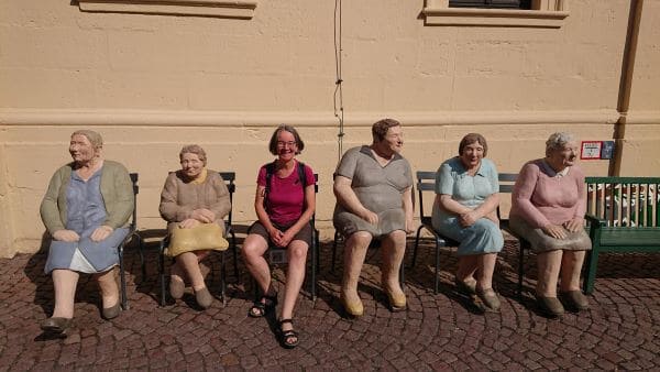 Heike Brandl inmitten von Frauenfiguren auf Stühlen in Fulda