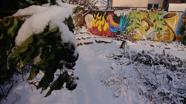 verschneiter Garten mit buntem Gemälde über Jesu Kreuzweg