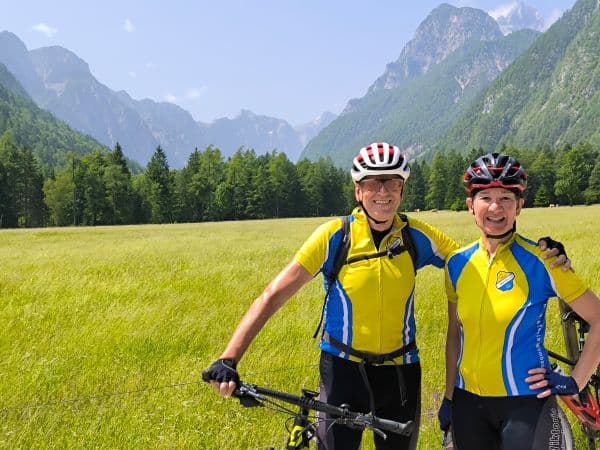 Slowenische Berge, Mann und Frau mit MTB vor einer Wiese und blauen Himmel