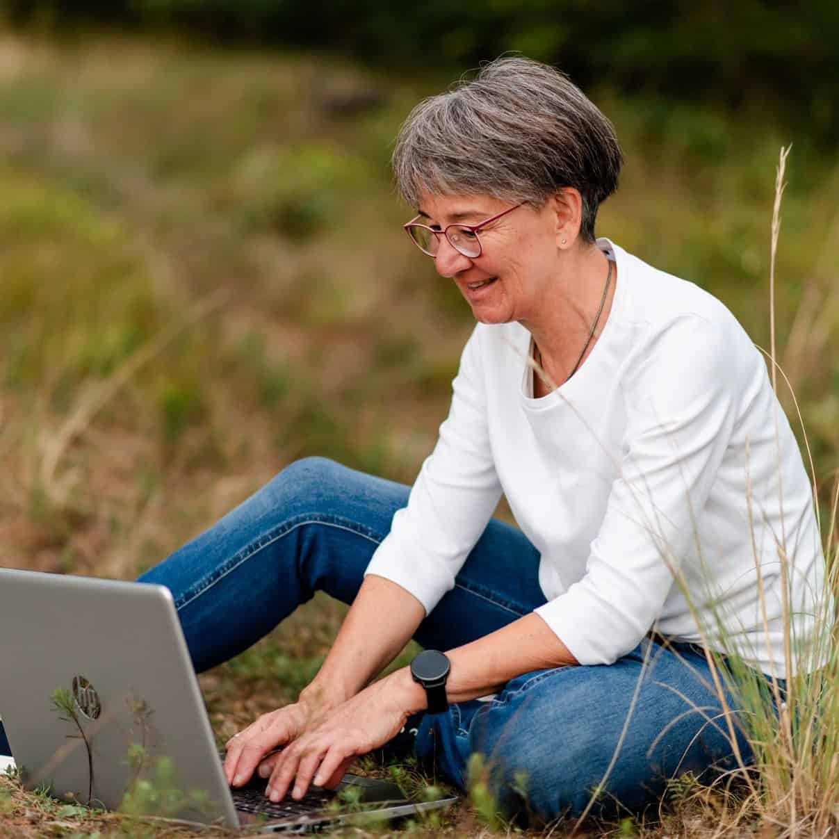 Heike Brandl - Trainerin für Kommunikation und Stressregulation am Laptop auf einer Wiese