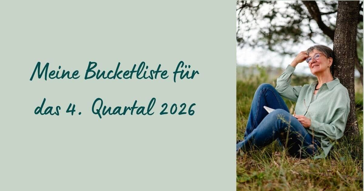 Heike Brandl sitzt an einen Baum gelehnt auf der Wiese, lächelnd, mit Notizbuch in der Hand